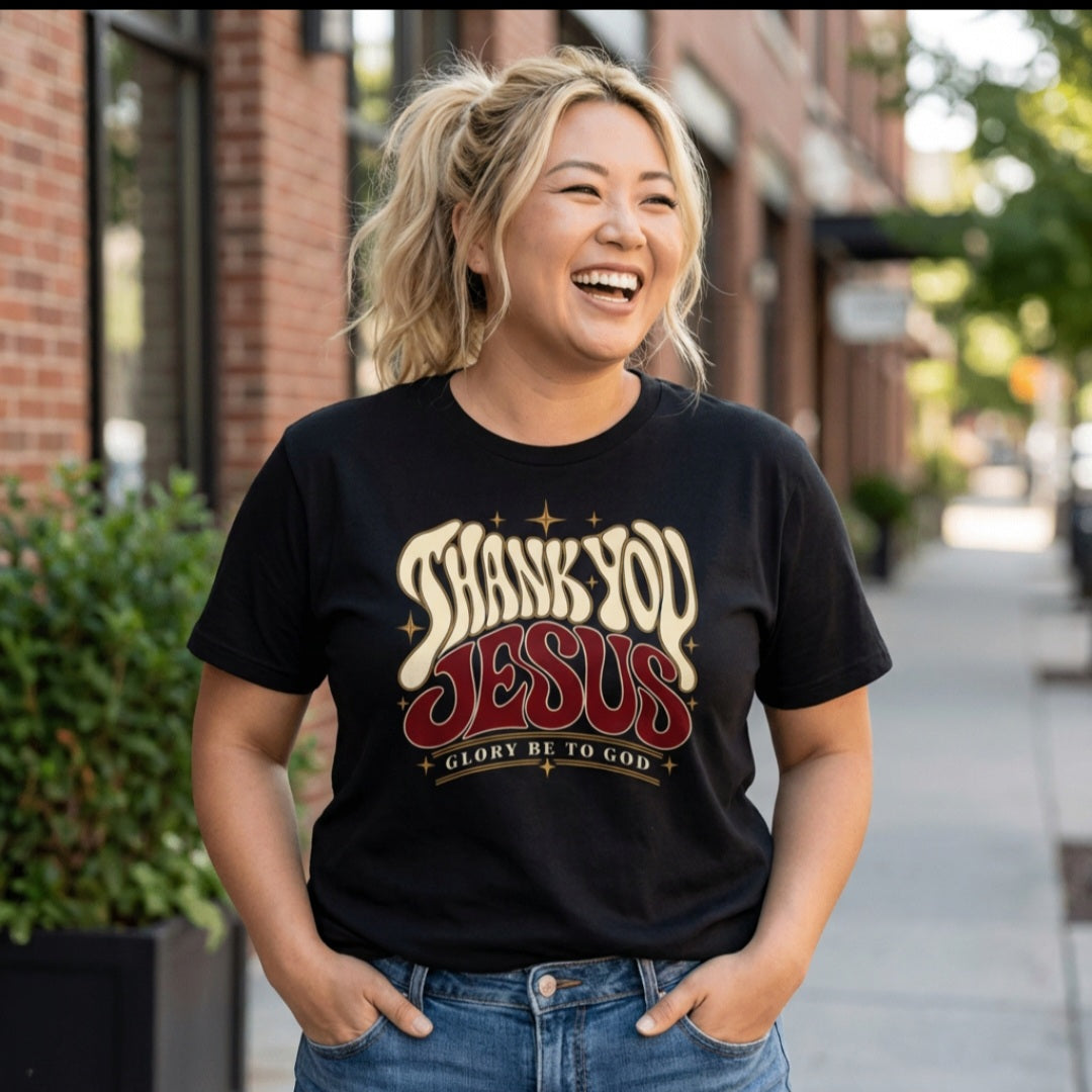 Woman wearing a black Sister Style Thank You Jesus t-shirt outdoors, with cream and deep red retro lettering and “Glory Be to God” beneath.
