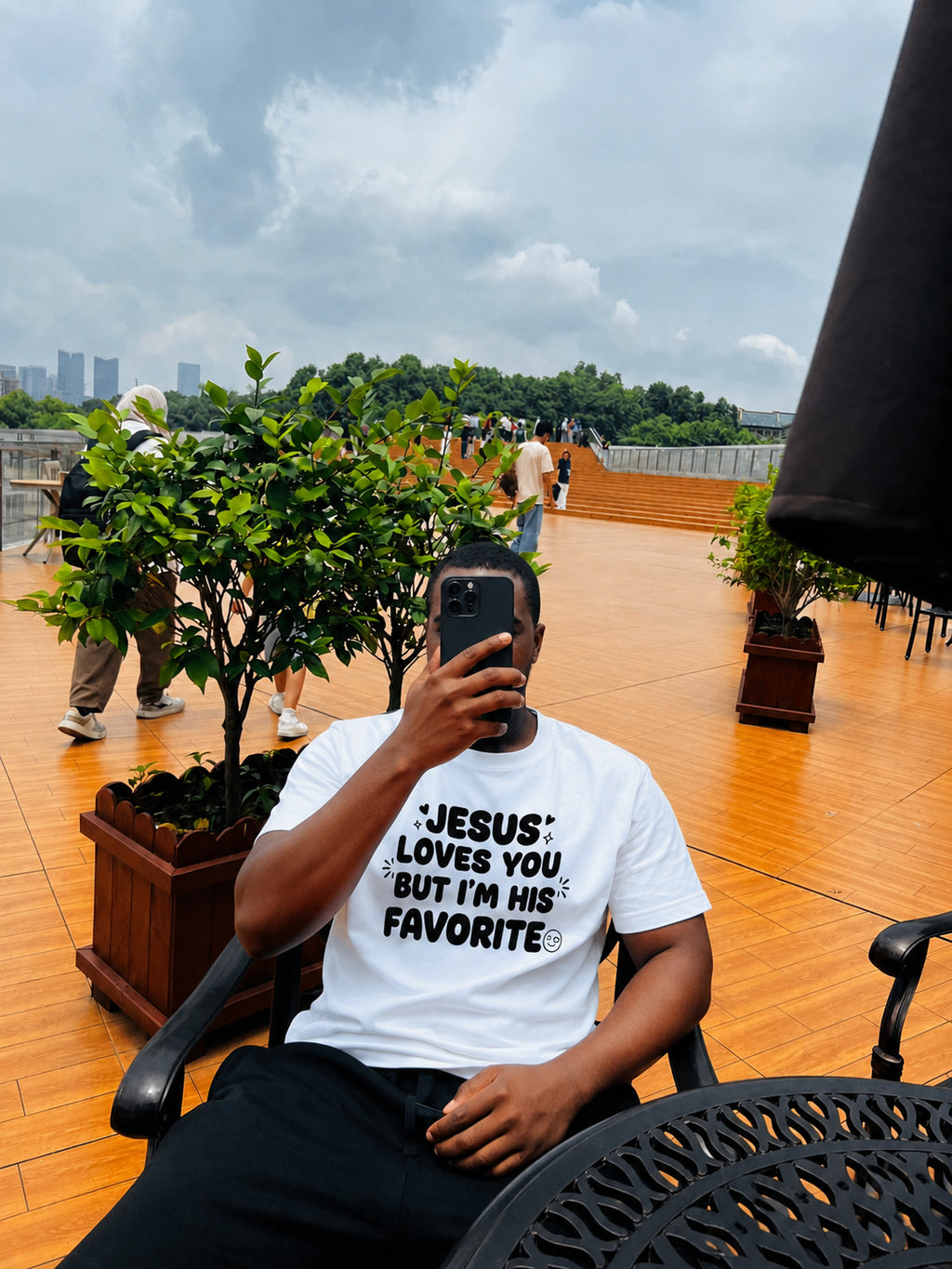 Man wearing Jesus Loves You But I'm His Favorite white tee by Sister Style — Christian faith humour streetwear African diaspora