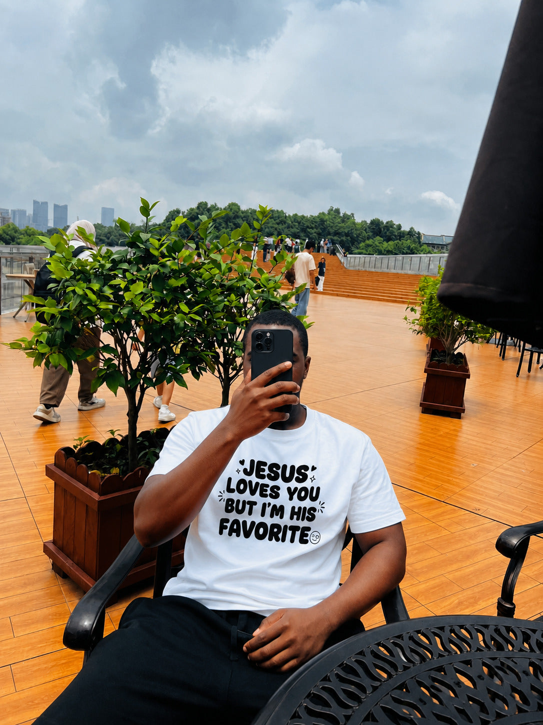 Man wearing Jesus Loves You But I'm His Favorite white tee by Sister Style — Christian faith humour streetwear African diaspora