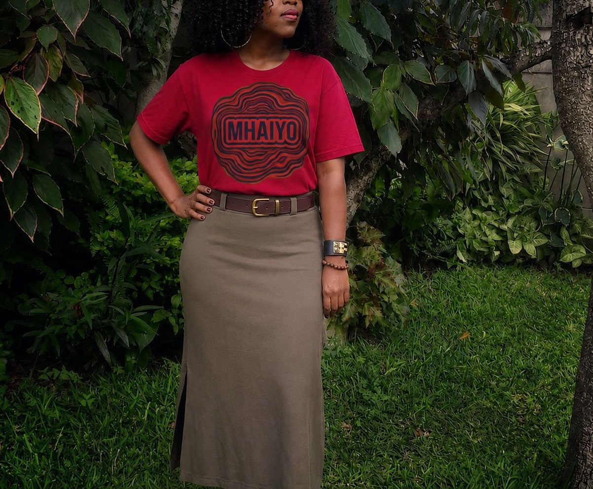 Woman wearing Mhaiyo red tee by Sister Style in a garden — Shona African heritage Zimbabwe diaspora streetwear
