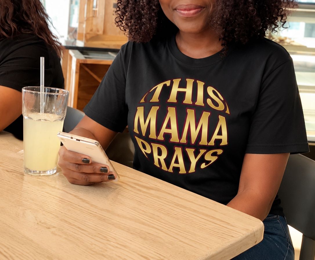Woman wearing This Mama Prays tee by Sister Style — Christian faith African heritage praying mum streetwear Zimbabwe