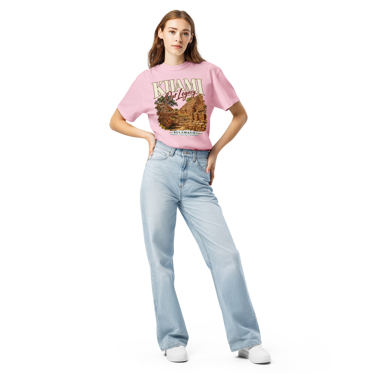 Model wearing pink: Model wearing a blossom pink Sister Style Khami heritage t-shirt tucked into jeans, showing the stone ruins design.