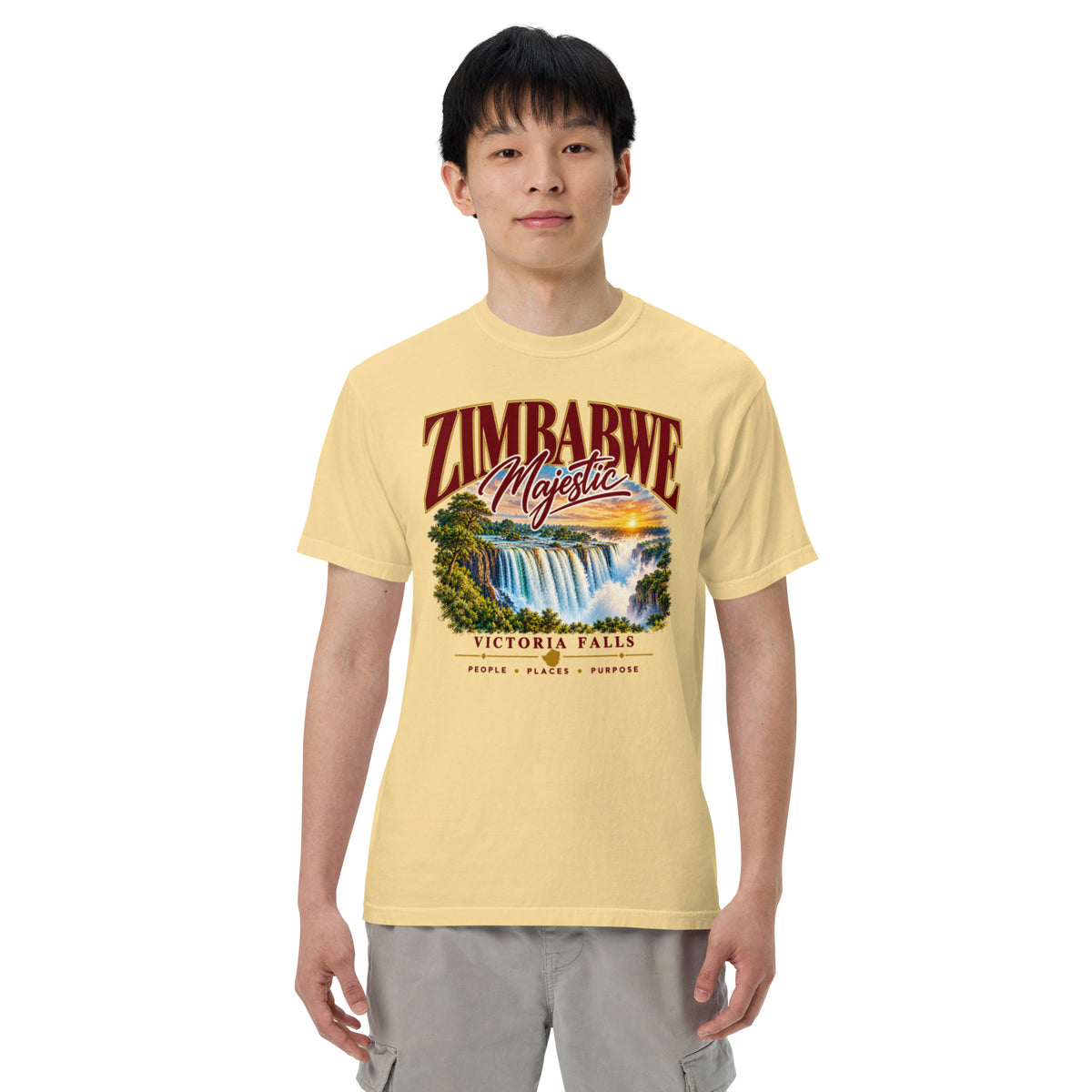 Model wearing a butter yellow Sister Style Victoria Falls t-shirt, showing waterfall artwork and “Zimbabwe Majestic” lettering.