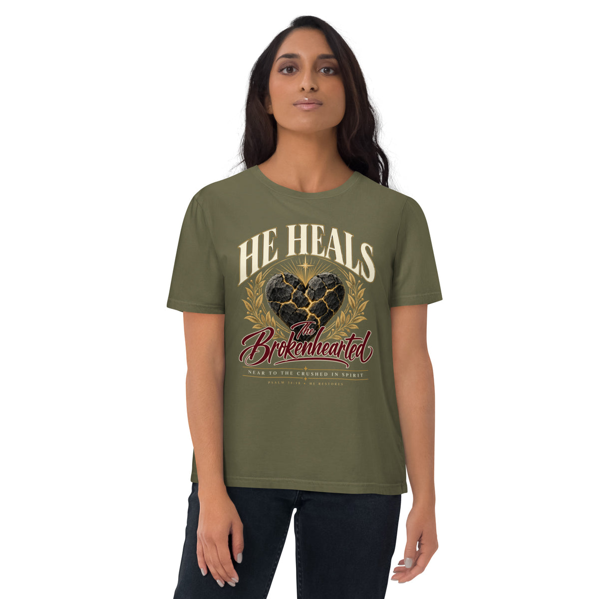 Woman wearing a Khaki He Heals the Brokenhearted organic cotton t-shirt with a cracked heart graphic and gold-coloured branches, front view.